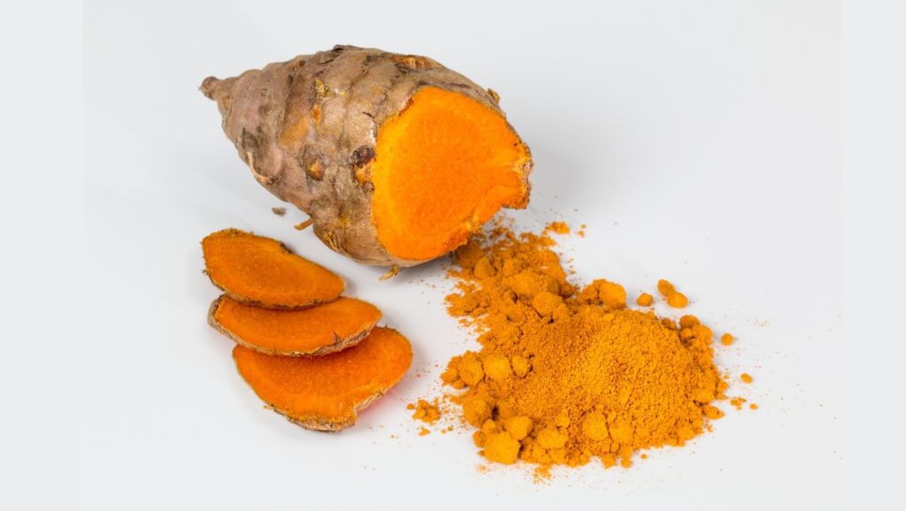 turmeric powder, turmeric roots, and turmeric supplements on top of a table