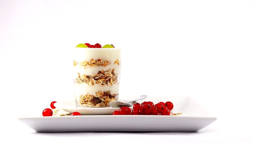 yogurt topped with seeds and granola and also positioned in a tiny white floral bowl